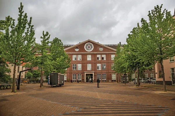 Bâtiment en briques et personnes par temps nuageux à Amsterdam — Photo