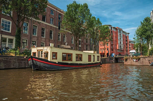 Oude bakstenen gebouwen in de buurt van Canal met afgemeerd boten in Amsterdam — Stockfoto