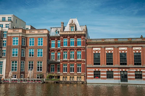 Brick buildings facade and restaurant on the canal in Amsterdam