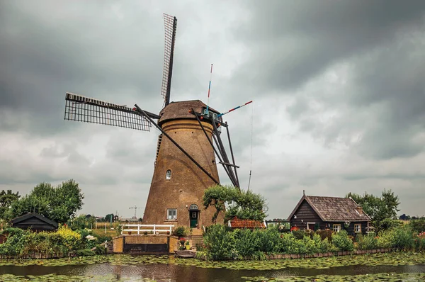 Molino de viento con casa y arbustos en el canal en Kinderdijk — Foto de Stock