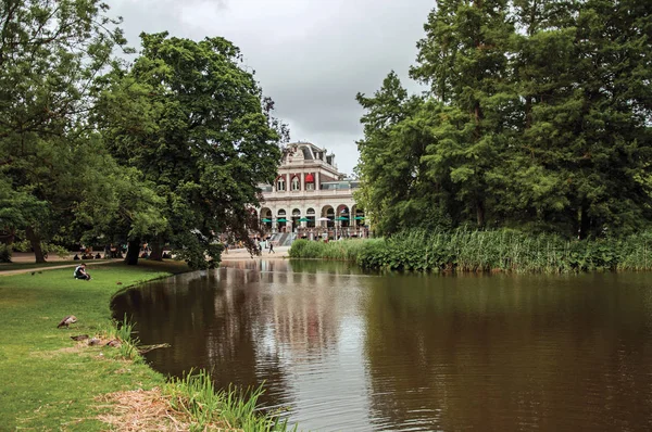 アムステルダム公園の木々、建物、曇り空の湖 — ストック写真