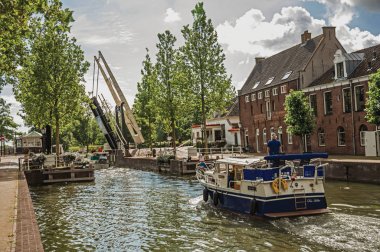 Weesp'te ağaçlarla çevrili bir kanalın yanından geçen tekne