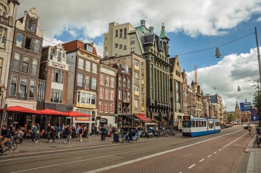 Tramvay, binalar ve Amsterdam'da birçok insan ile Sokak