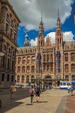 Amsterdam'da bir sokak ve tuğla binanın önünden yürüyen insanlar