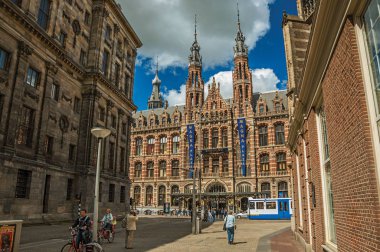 Amsterdam'da bir sokak ve tuğla binanın önünden yürüyen insanlar