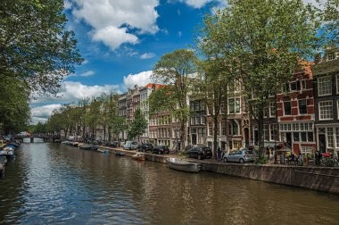 Amsterdam'da eski tuğla binalar ve demirli tekneler ile Kanal