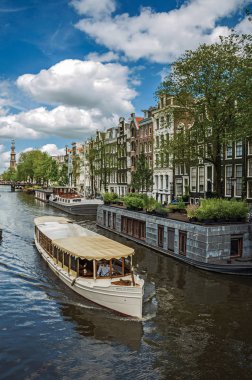 Amsterdam'da eski tuğla binalar ve demirli tekneler ile Kanal