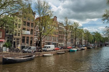Amsterdam'da eski tuğla binalar ve demirli tekneler ile Kanal