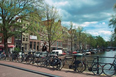 Amsterdam'da bisiklet ve eski binalar ile kanal üzerinde Köprü