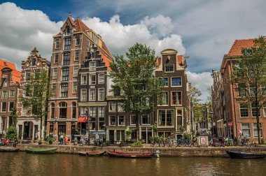 Amsterdam'da eski tuğla binalar ve demirli tekneler ile Kanal
