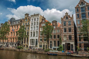 Amsterdam'da eski tuğla binalar ve demirli tekneler ile Kanal