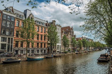 Amsterdam'da eski tuğla binalar ve demirli tekneler ile Kanal
