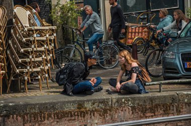 Amsterdam'da kanal da oturan sokak ve gençler