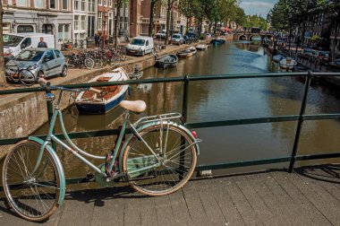 Amsterdam'da korkulukta bisikletle kanal üzerinde köprü