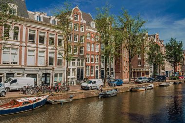 Amsterdam'da eski tuğla binalar ve demirli tekneler ile Kanal