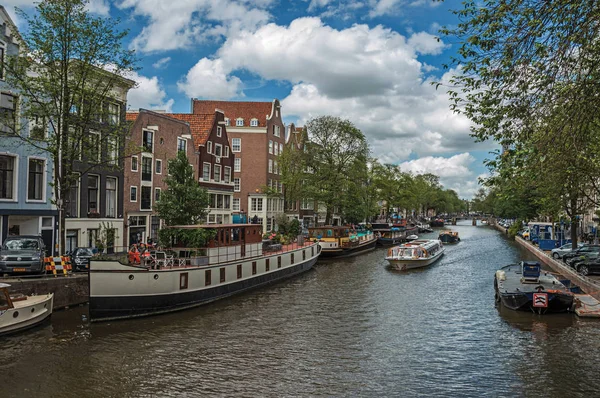 Канал зі старими цегляними будівлями і Швартовані човни в Амстердамі — стокове фото