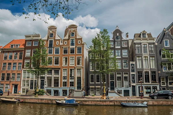 Kanaal met oude bakstenen gebouwen en afgemeerde boten in Amsterdam — Stockfoto