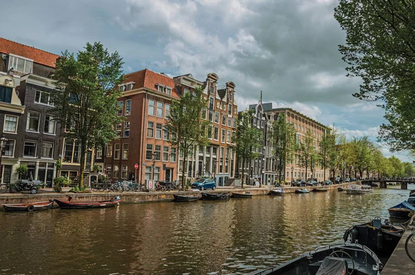 Canal com velhos edifícios de tijolos e barcos ancorados em Amsterdã — Fotografia de Stock