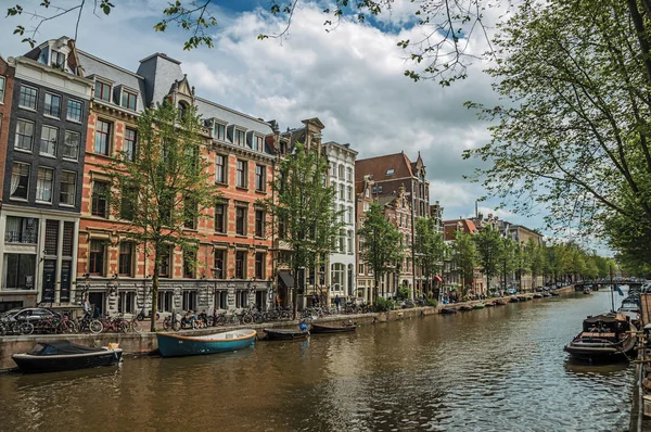 Канал зі старими цегляними будівлями і Швартовані човни в Амстердамі — стокове фото