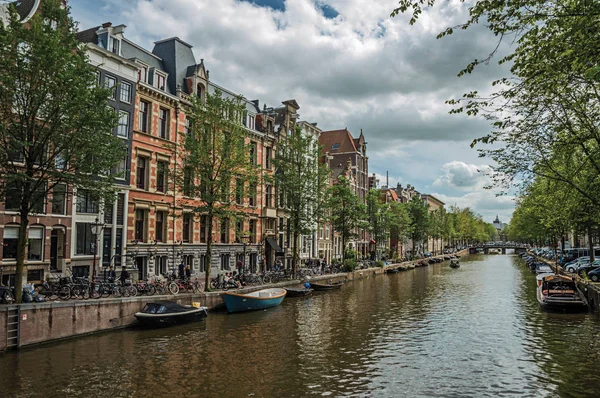 Canal com velhos edifícios de tijolos e barcos ancorados em Amsterdã — Fotografia de Stock