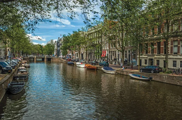 Kanaal met oude bakstenen gebouwen en afgemeerde boten in Amsterdam — Stockfoto