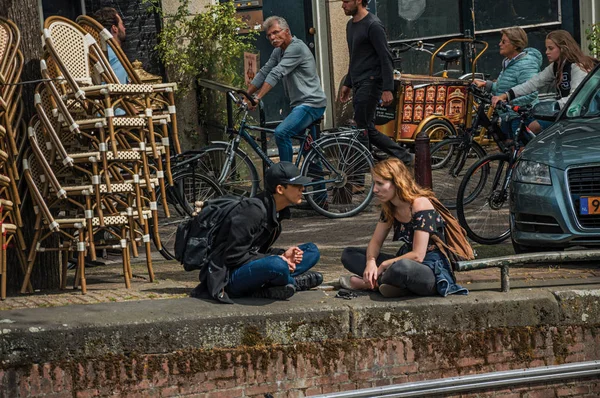 Calle y jóvenes sentados junto al canal en Amsterdam — Foto de Stock