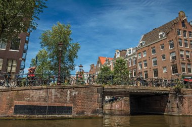 Amsterdam'da bisikletli kanal üzerinde tuğla binalar ve köprü