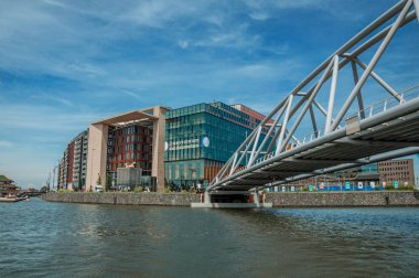Amsterdam'da güneşli mavi gökyüzü altında bina ve demir köprü