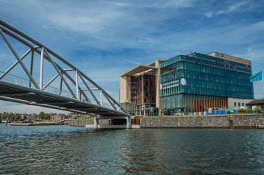 Amsterdam'da güneşli mavi gökyüzü altında bina ve demir köprü