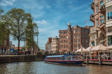 Amsterdam'da tuğla bina ve turistik tekne ile Kanal