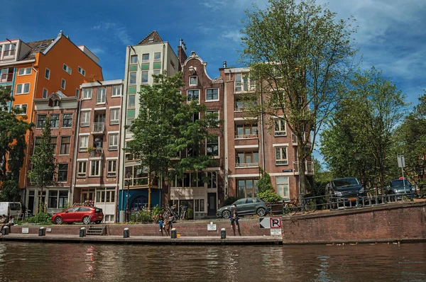 Kanaal met oude bakstenen gebouwen en mensen in Amsterdam — Stockfoto