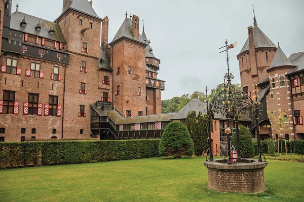 De Haar Castillo de fachada con pozo adornado, jardín de césped y torre de ladrillo — Foto de Stock