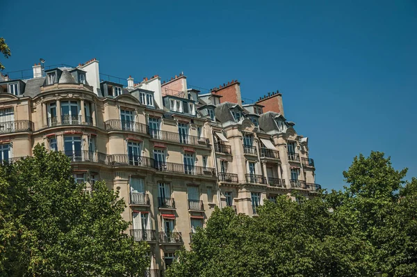 Budova uprostřed stromů a modrá obloha v Paříži — Stock fotografie