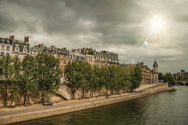Paris'te güneş ışığı ile Seine Nehri üzerinde eski binalar ve kaldırım