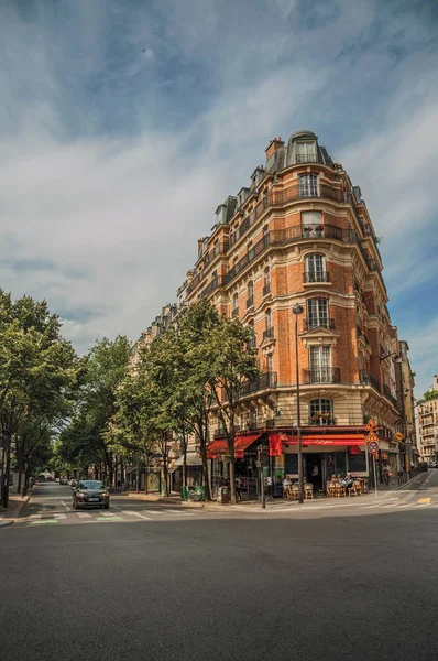 Rohová cihlová budova s restaurací a stromy v Paříži — Stock fotografie