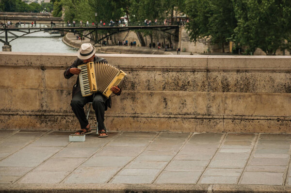 Old man playing accordion over bridge at the Seine River in Paris