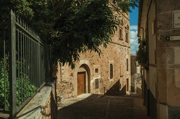 Beco com escadaria em meio a velhos edifícios de pedra e árvores floridas em Cáceres — Fotografia de Stock