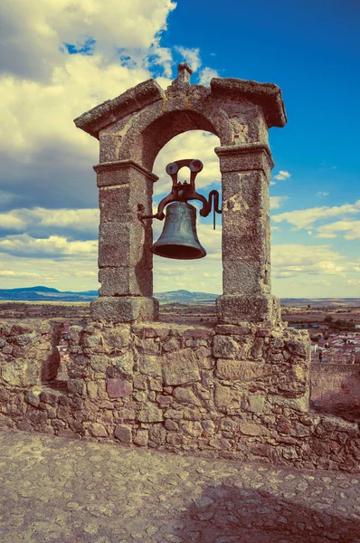 Bronze bell on top of stone wall at the Castle of Trujillo