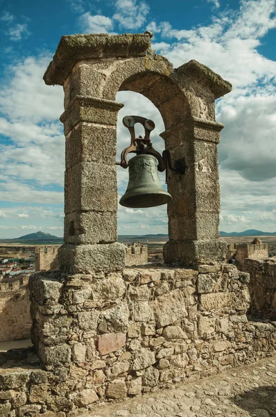 Bronze bell on top of stone wall at the Castle of Trujillo
