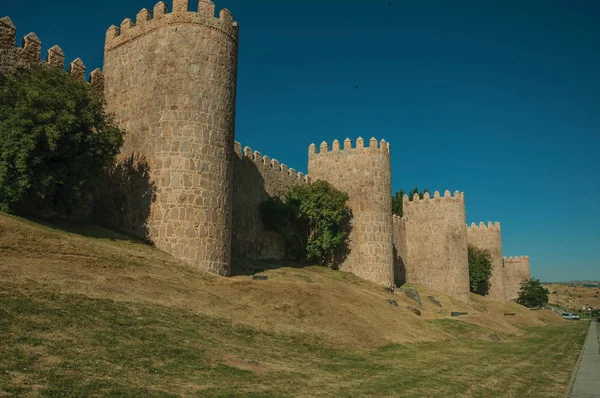 Torres de pedra na grande muralha da cidade e gramado verde em Avila — Fotografia de Stock