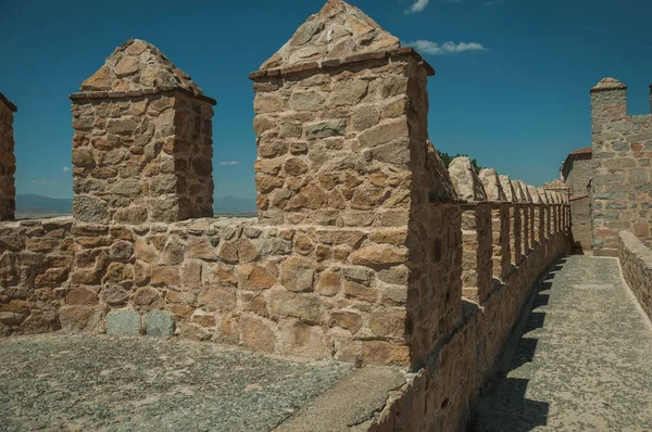 Pathway over thick stone wall with battlement around Avila