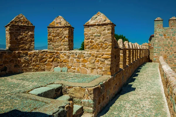 Pathway over thick stone wall with battlement around Avila