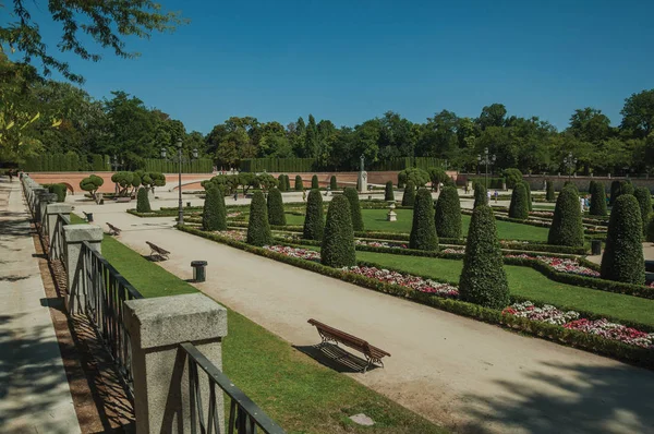 Pathway on gardens with trees and benches in a park of Madrid