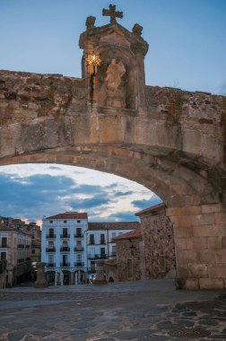 Caceres alacakaranlıkta Our Lady ve eski binaların heykeli ile Kemer ağ geçidi
