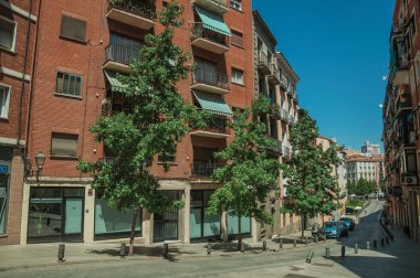 Madrid'de sakin bir sokakta tuğla cephe ve ağaçlar ile Bina