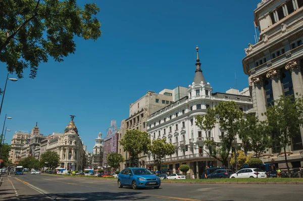 Edificios en la concurrida calle con gente y coches en Madrid — Foto de Stock