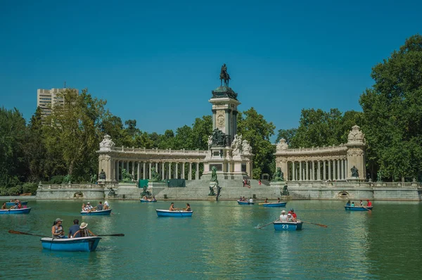 Personas con embarcaciones en piscina frente al monumento en un parque de Madrid — Foto de Stock