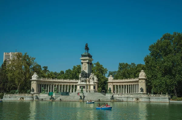Pessoas com barcos na piscina em frente ao monumento em um parque de Madrid — Fotografia de Stock