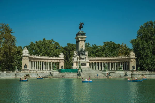 Personas con embarcaciones en piscina frente al monumento en un parque de Madrid — Foto de Stock