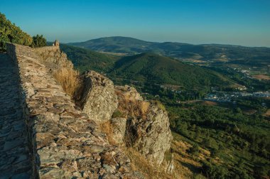 Küçük gözetleme kulesi ve dağlık manzara ile uçurum üzerinde taş duvar